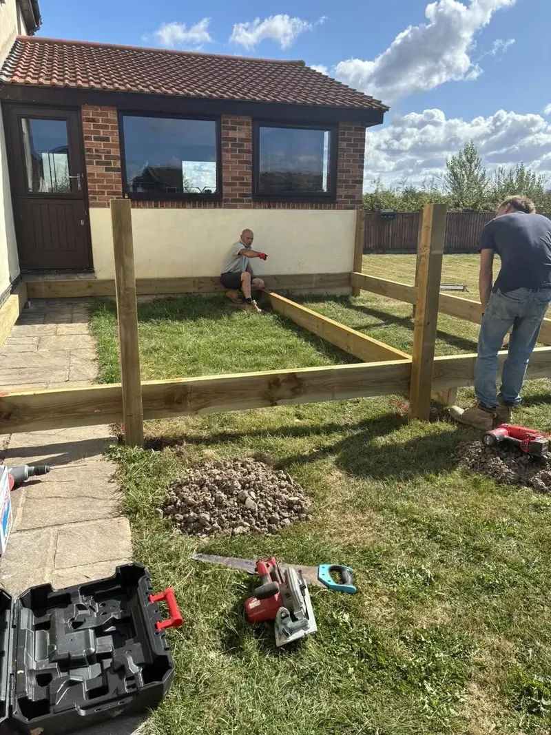 Timber posts and the deck frame set out on the lawn behind a house