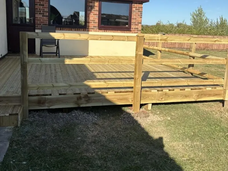 A raised timber deck part built behind a house, boards going down over the frame