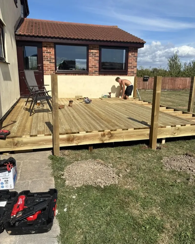 Laying the boards of a raised timber deck behind a house