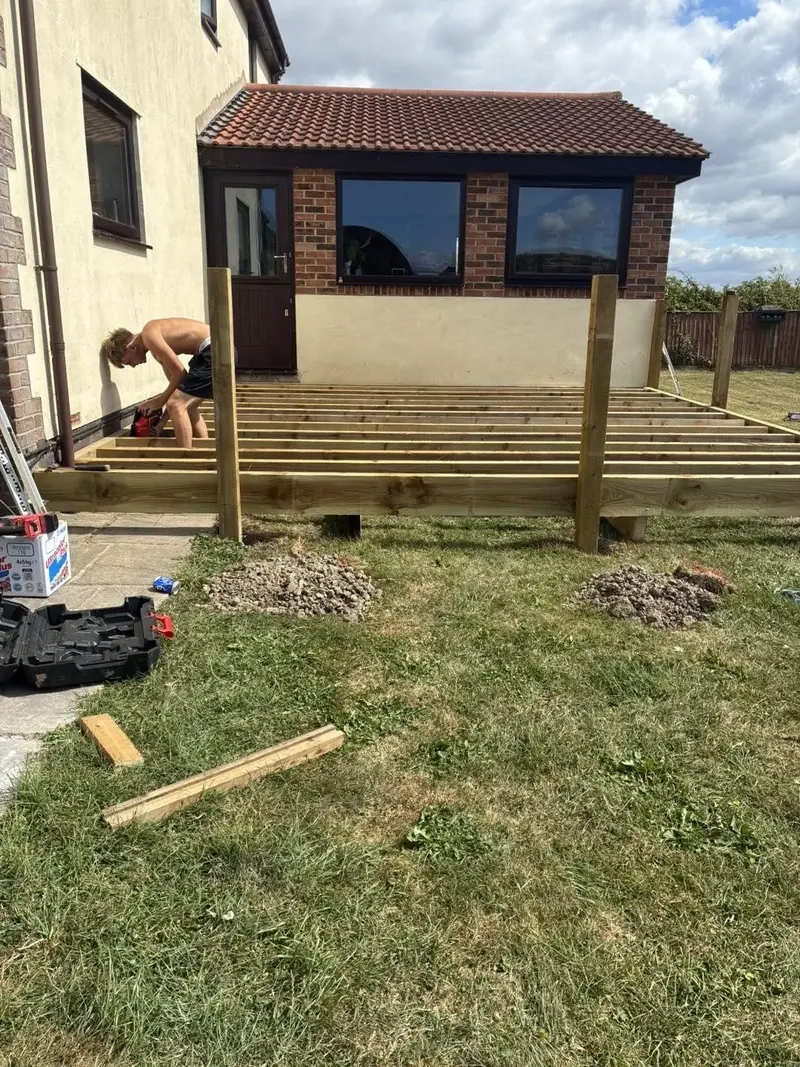 The deck boards laid towards the house, posts standing along the edge