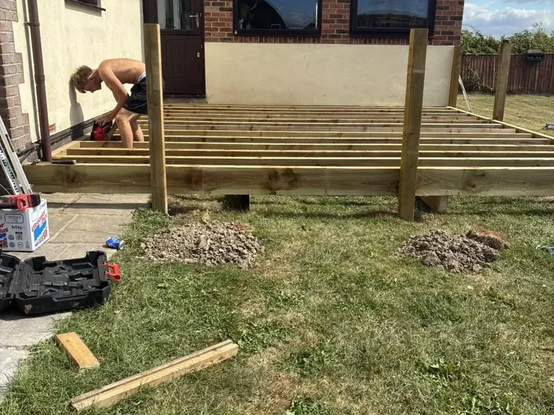 The joists fixed across the deck frame beside the house