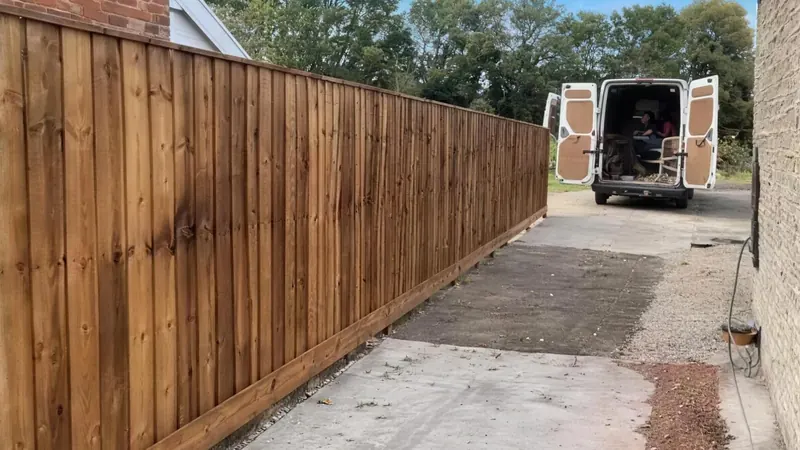 A long new closeboard fence running down a gravel drive