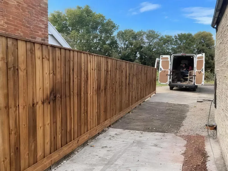 A new closeboard fence running down a gravel drive, a van parked at the end