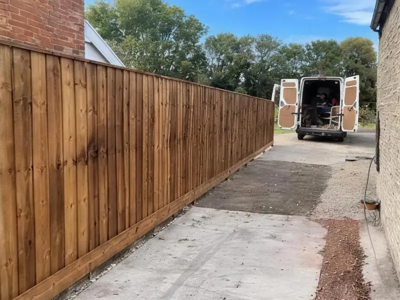 A long new closeboard fence running down a gravel drive