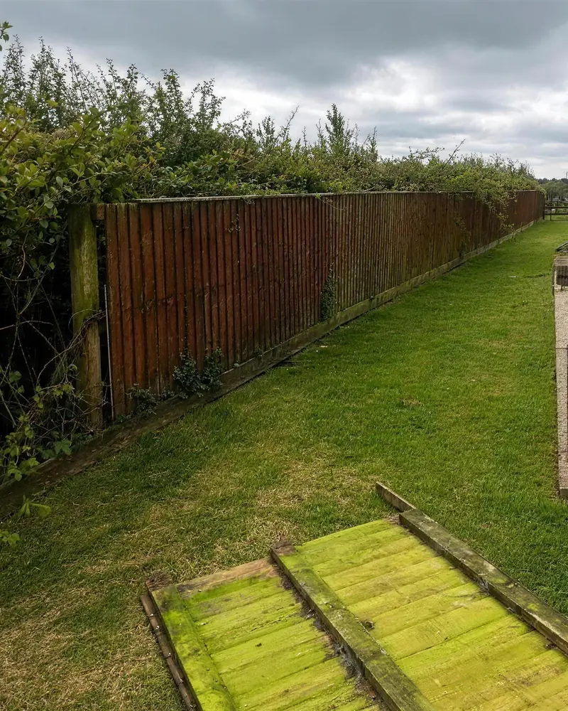 Before: the old weathered fence along a side lawn, a rotten panel on the grass