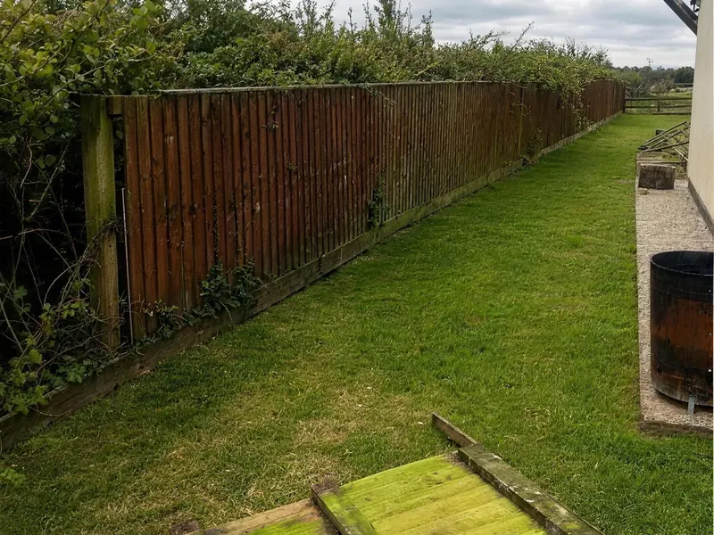 Before: an old weathered fence along a side lawn, a rotten panel down on the grass