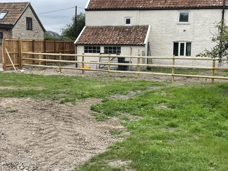 Post and half-round rail fencing with stock wire along a paddock edge