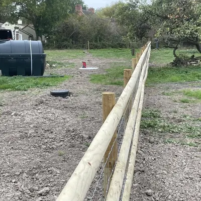 Post and rail fencing with stock wire along a field